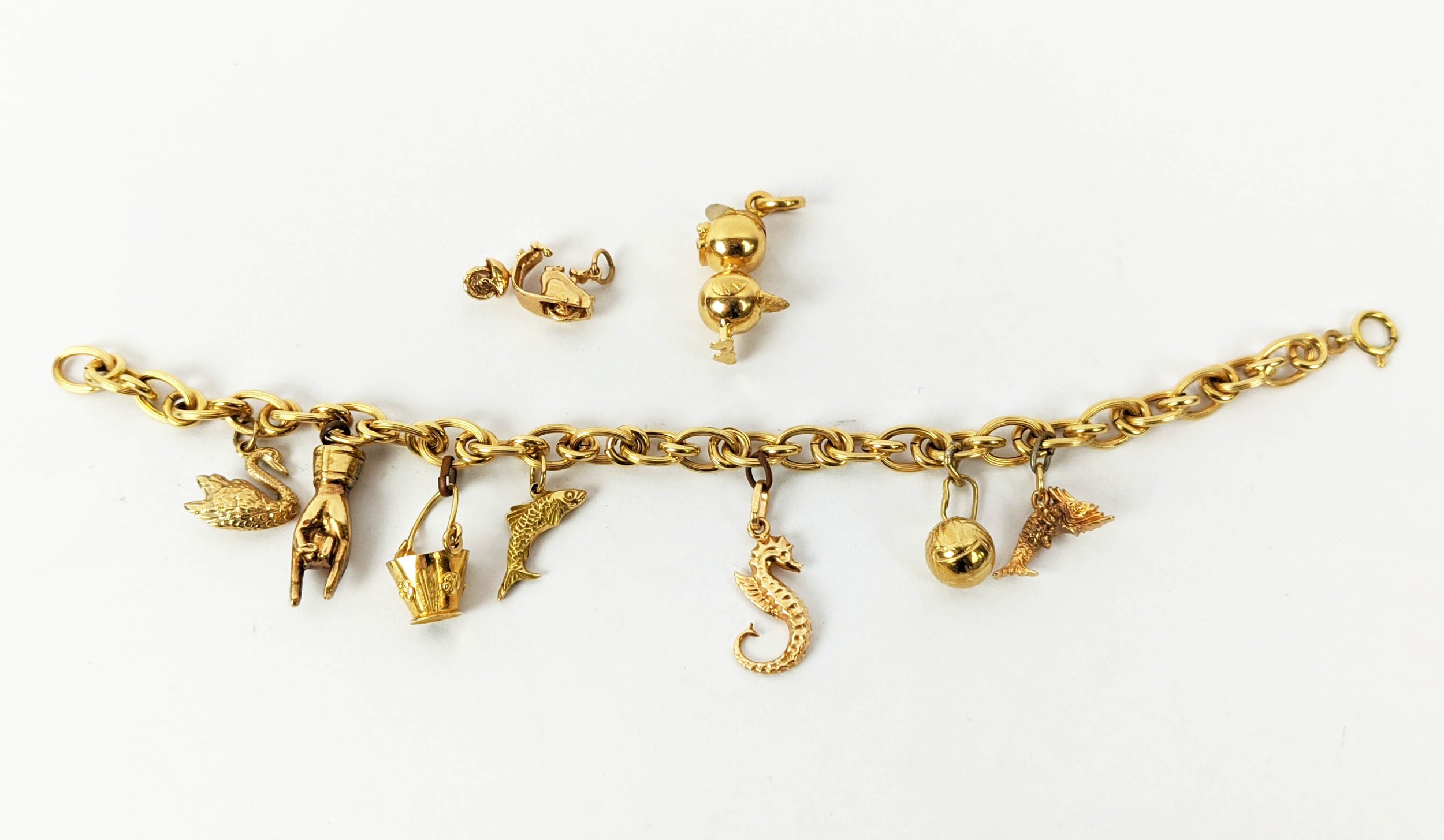 AN 18CT GOLD CHARM BRACELET, fitted with seven charms, plus two further loose charms, 21cm long,