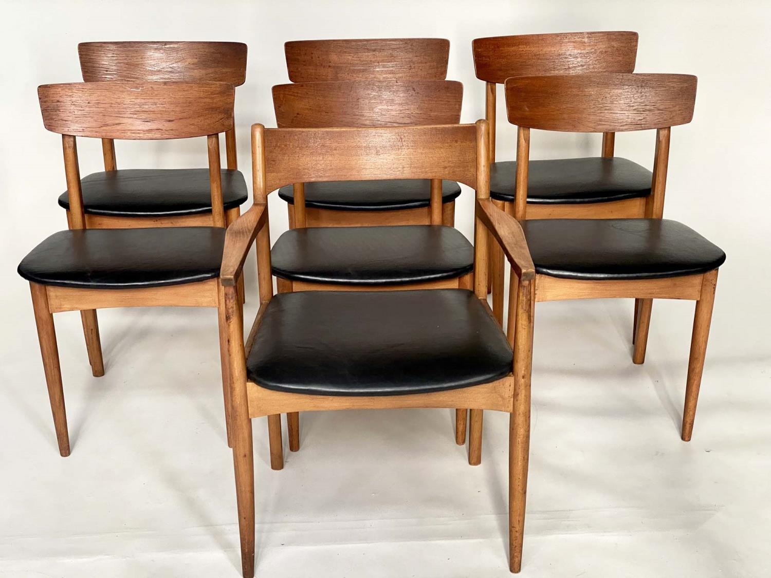 DINING CHAIRS, a set of seven, 1970's teak Danish style with black leather seats and carved backs