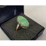 AN 18CT GOLD AND JADE SET DRESS RING, the single jade cabouchon in a white metal pierced setting,