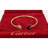 A CARTIER 18CT GOLD BANGLE, set with mother-of-pearl and black onyx roundel terminals, each