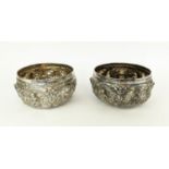 BURMESE BOWLS, a pair, probably late 19th Century, white metal with embossed decoration in high