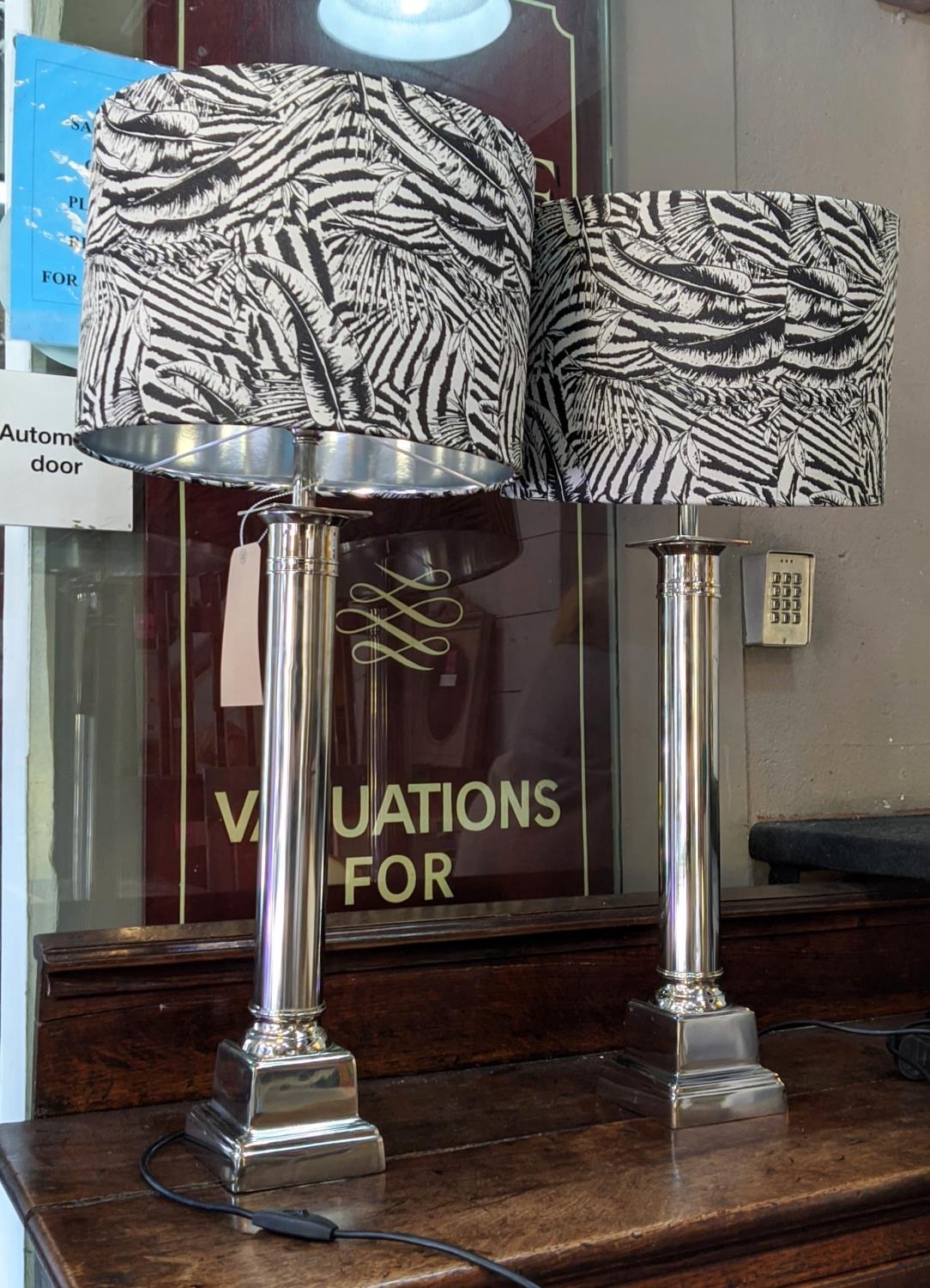 TABLE LAMPS, a pair, polished metal column design, black and white foliate print shades, 81cm H x