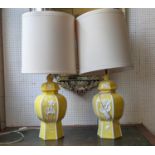 A PAIR OF YELLOW CERAMIC LAMPS, hexagonal form, white floral decoration in relief, cream shades,