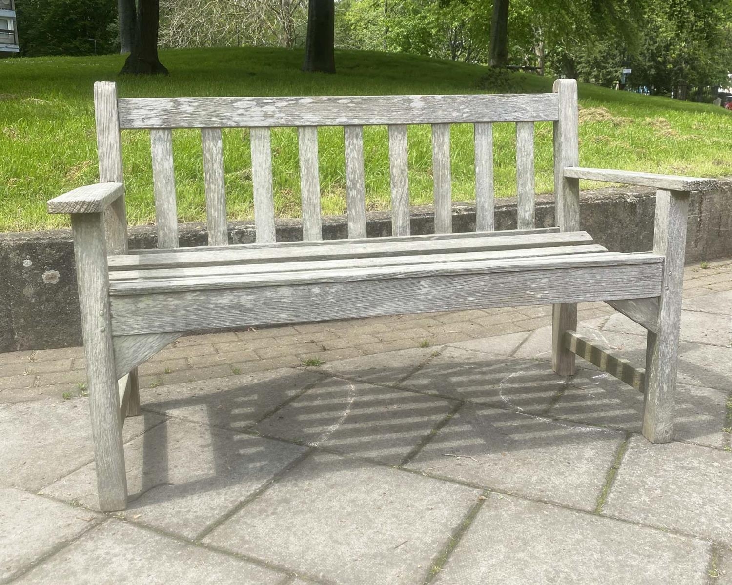 LISTER GARDEN BENCH, silvery weathered teak of slatted construction with flat top arms by R A Lister