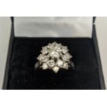 AN 18CT WHITE GOLD AND PLATINUM DIAMOND SET FLOWER HEAD CLUSTER RING, the central round brilliant