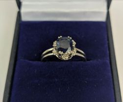 A SAPPHIRE AND DIAMOND SET DRESS RING, the single stone sapphire of approximately 1 carat, claw