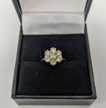 AN 18CT WHITE GOLD DIAMOND FLOWER HEAD SEVEN STONE CLUSTER RING, the central brilliant cut stone