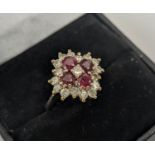 AN 18CT WHITE GOLD RUBY AND DIAMOND DRESS RING, set with four rubies and a central diamond,
