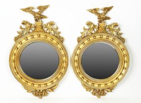 WALL MIRRORS, a pair, Regency design, gilt circular frames with an eagle surmount, 90cm x 56cm. (2)