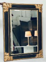 WALL MIRROR, Italian style ebonised and parcel gilt with bevelled mirror and bold acanthus