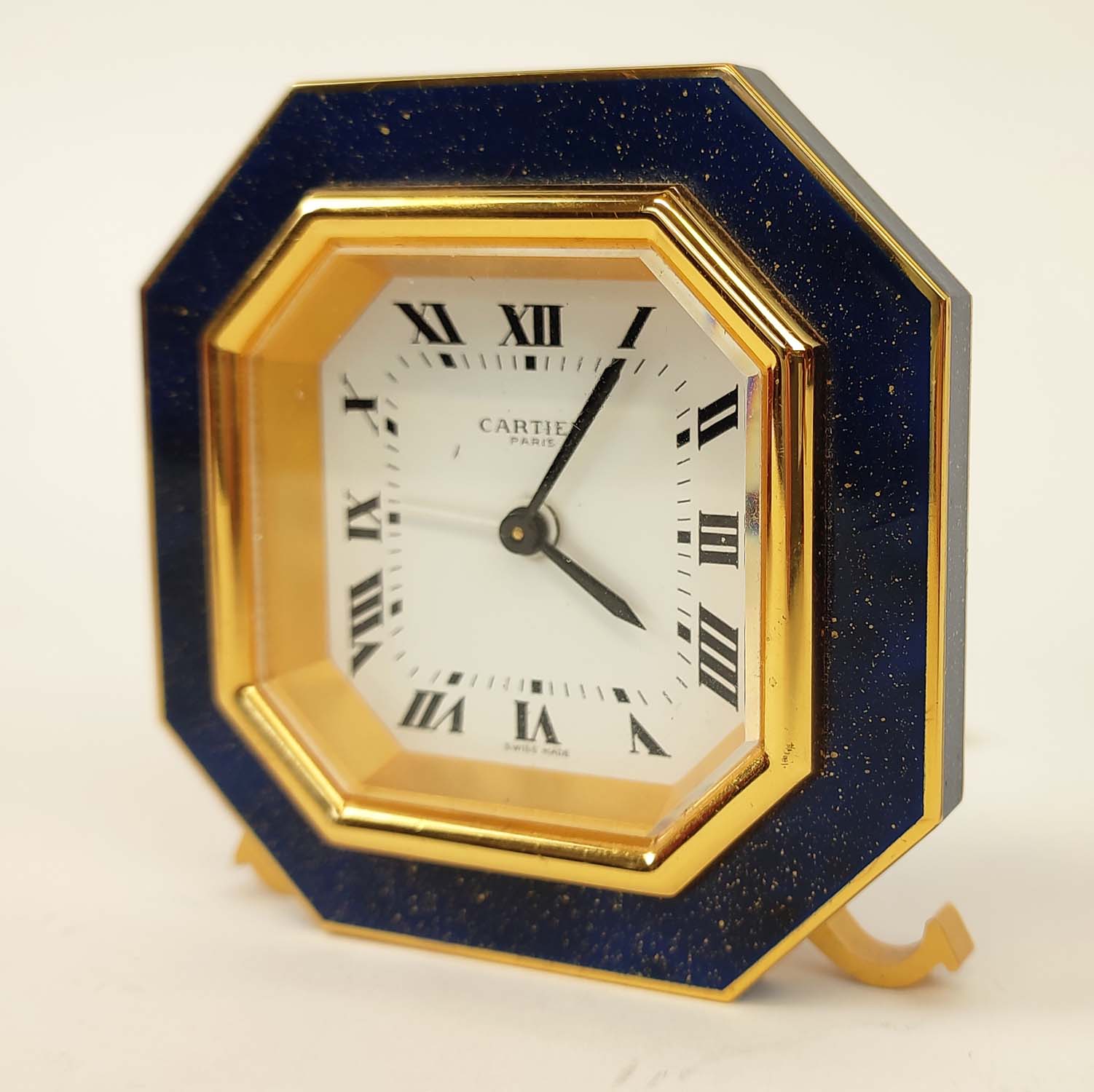 A CARTIER TRAVELLING CLOCK, simulated lapis lazuli enameled gilt octagonal case, white dial with