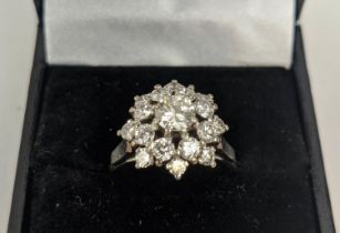AN 18CT WHITE GOLD AND PLATINUM DIAMOND SET FLOWER HEAD CLUSTER RING, the central round brilliant
