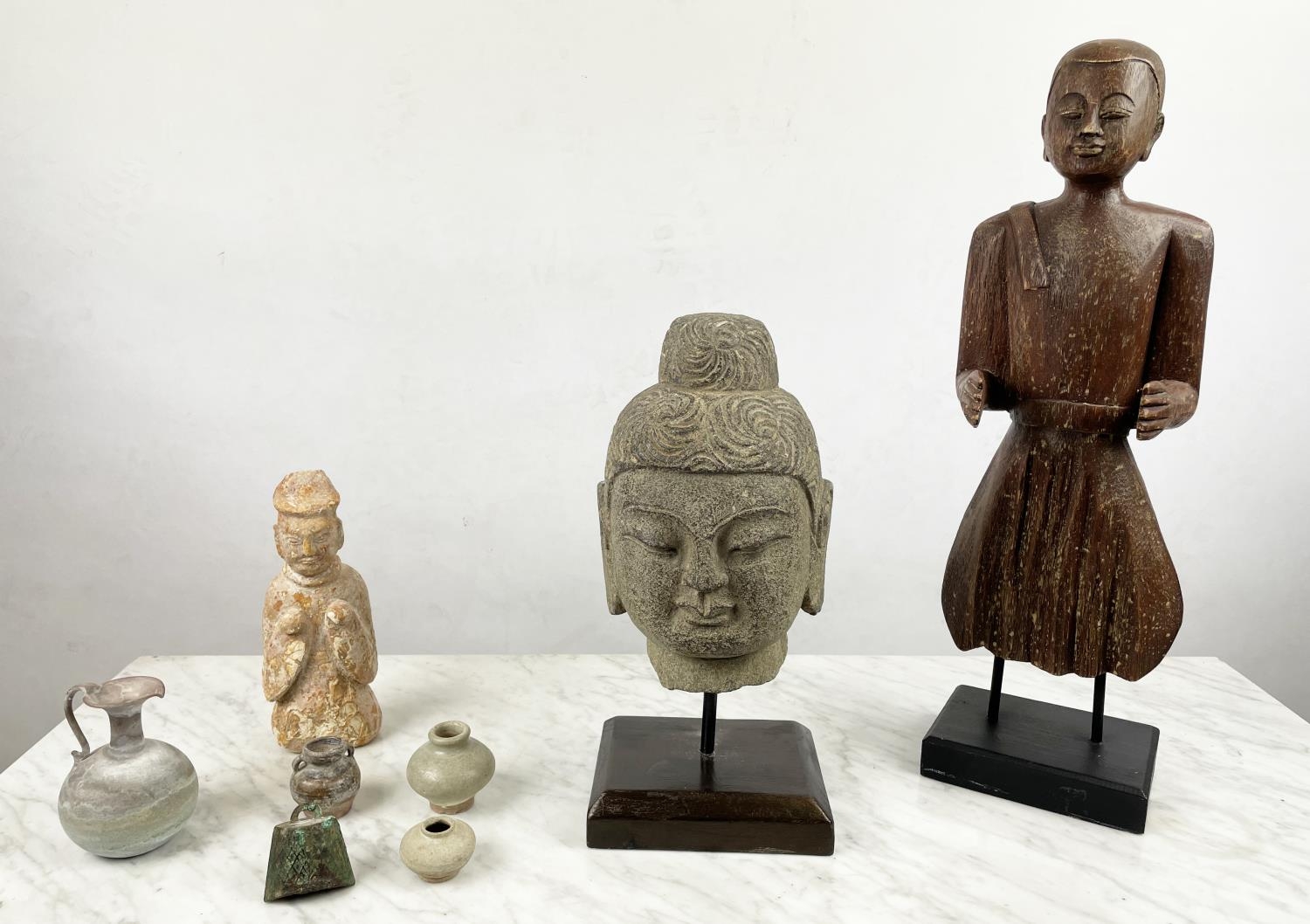 A CARVED STONE BUDDHA HEAD ON STAND, an Oriental wood figure and a glazed pottery figure along