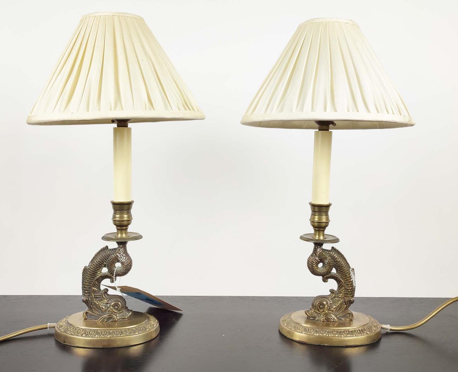TABLE LAMPS, a pair, each 43cm H overall, including shades, in the form of brass dolphins. (2)