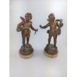 A pair of spelter winged putti, holding musical instruments