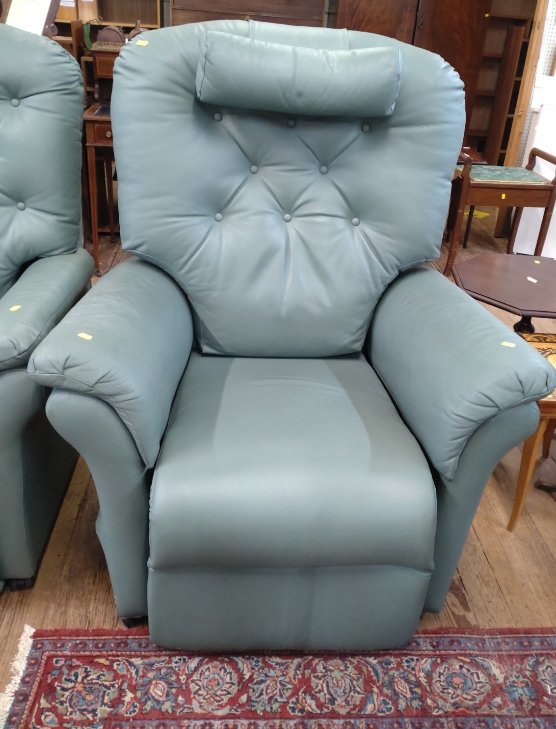 A green electric recliner armchair with fire label.