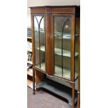 Glass bookcase: three shelves behind two doors. 170cm x 100cm x 31cm.