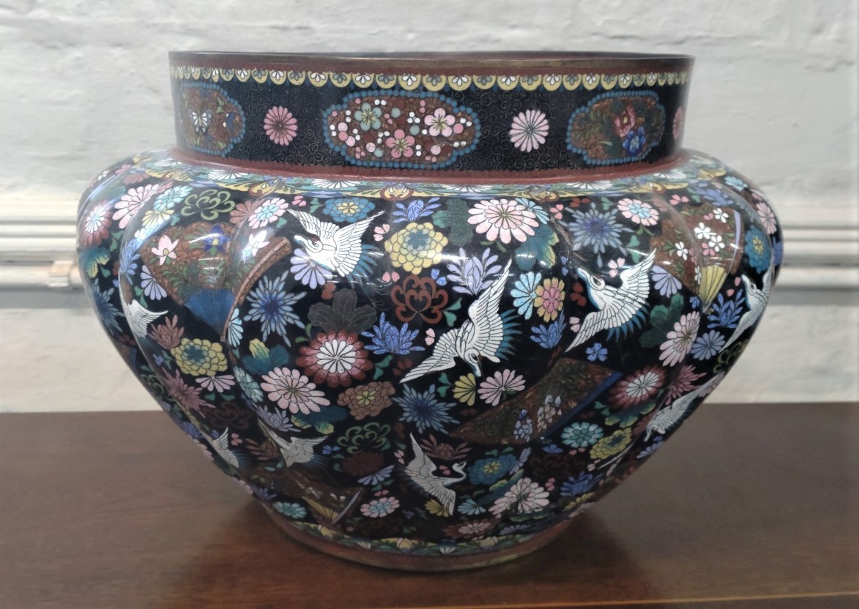 A cloisonne jardiniere decorated with cranes and flowers on black ground 38.5cm diameter, 26cm high