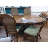 A shaped oval dining table and four wicker back chairs. Circa 1930. 76cm x 167cm x 110cm.