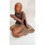 A Chinese hardwood Carving of a Buddha. 19th century. Part painted in red. Shown praying. 38cm high.