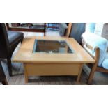 A square coffee table with a glass insert top and a shelf beneath.