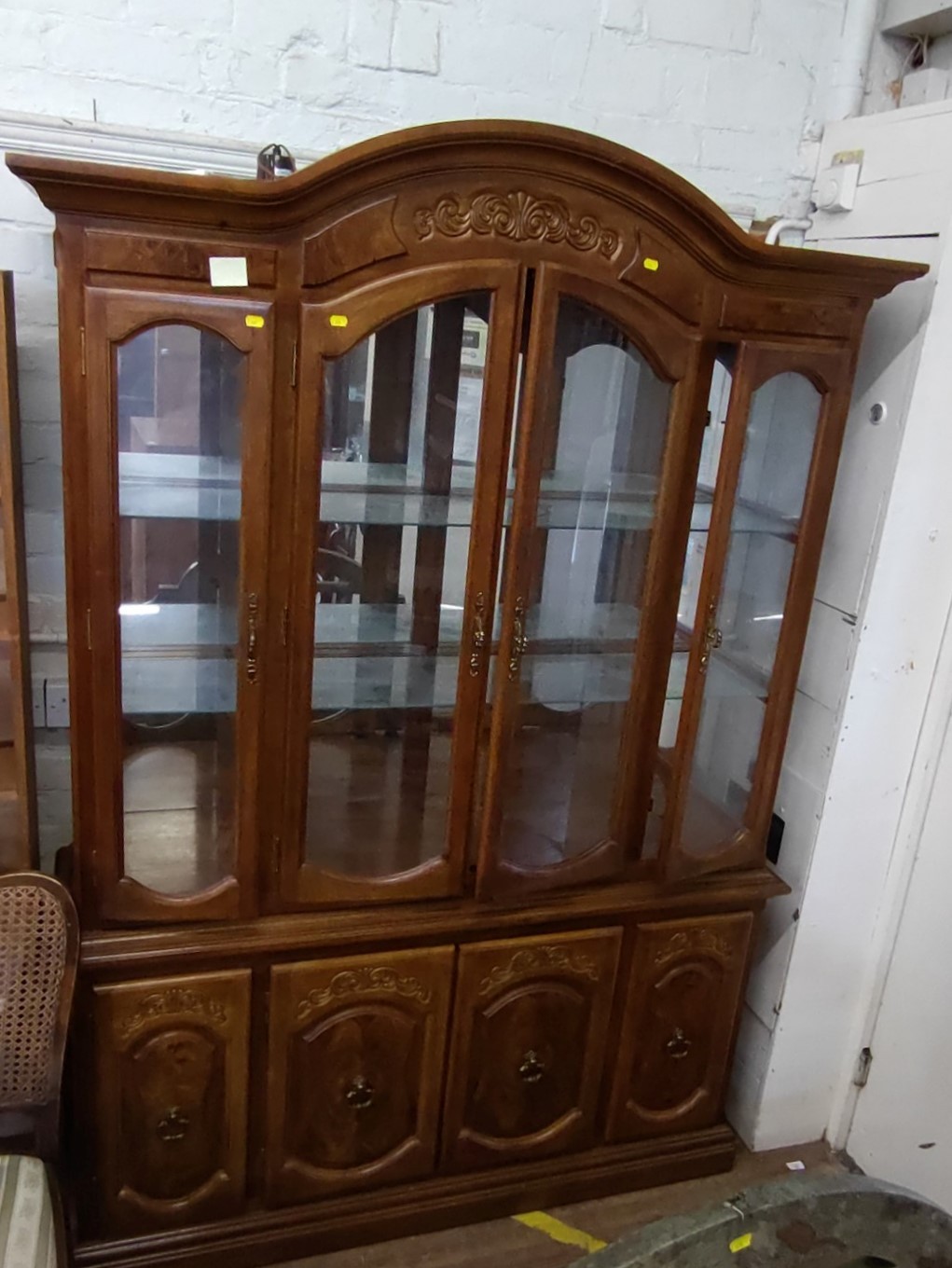 A large display cabinet. 20th century. With a pair of doors enclosing glass shelves. 210cm x 144cm x