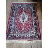 A red ground full pile Kashmir rug with traditional floral medallion design (170cm x 120cm)