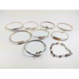 A bag containing nine silver bangles set with various gems and other.