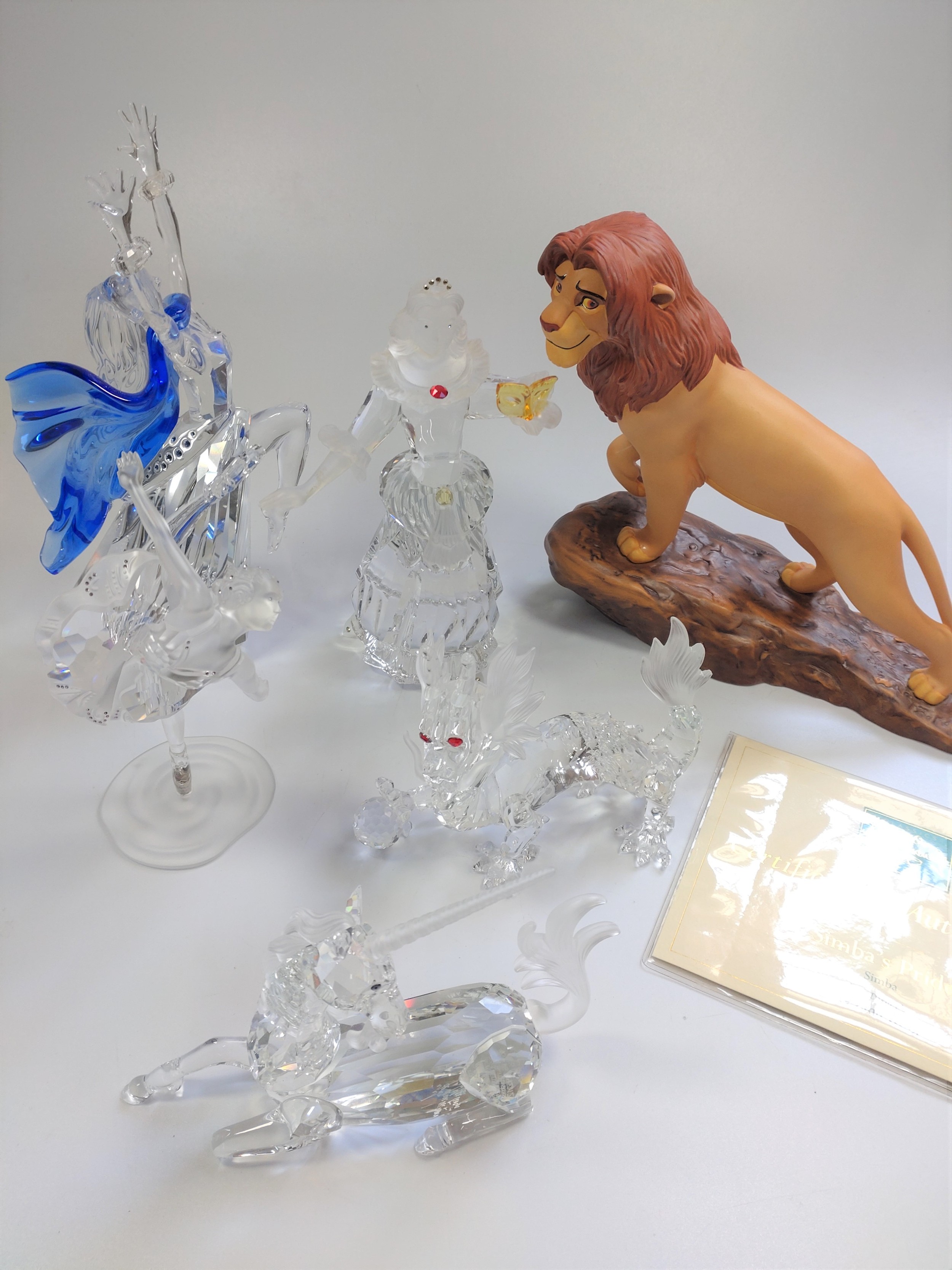 Three Swarovski cut glass dancers 14cm to 20cm, dragon and a unicorn; and a ceramic Simba from