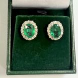 Pair of 18ct white gold oval emerald and Round Brilliant Cut diamond cluster studs,