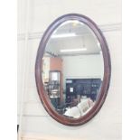 An Edwardian oval bevelled mirror. 82 x 60cm.