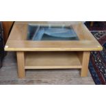 A modern square coffee table with a glass insert top and a shelf beneath. 38 x 90 x 90cm.