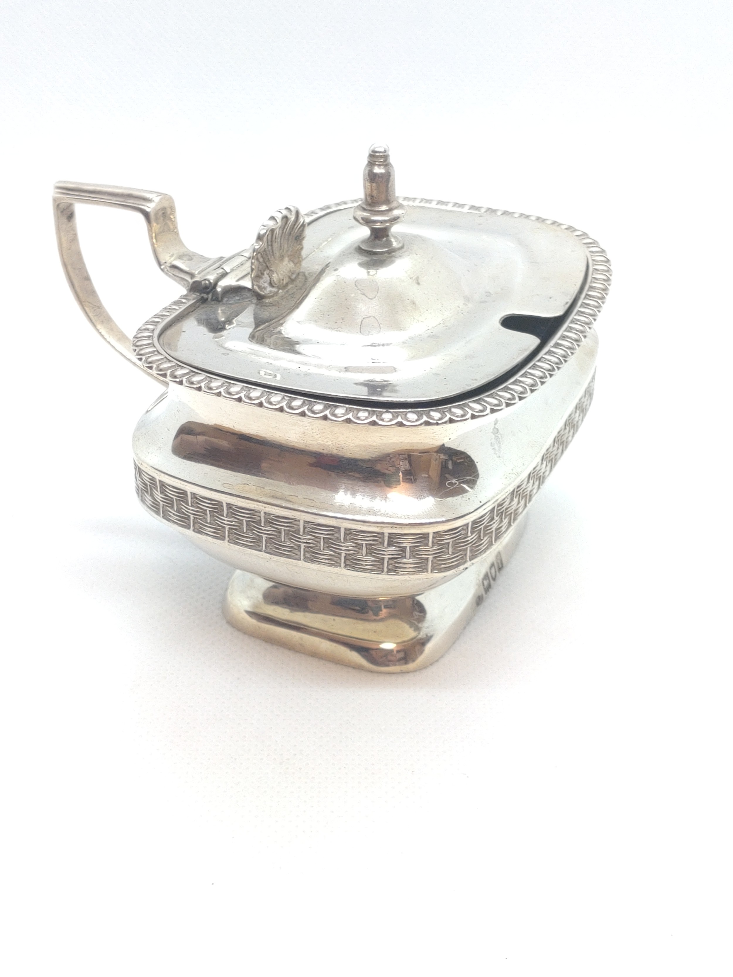 A sterling silver mustard pot in George III style. London 1903. 174gms excluding blue glass liner