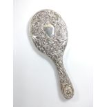 A sterling silver hand mirror embossed with winged cherubs and scrolling foliage. Goldsmiths and