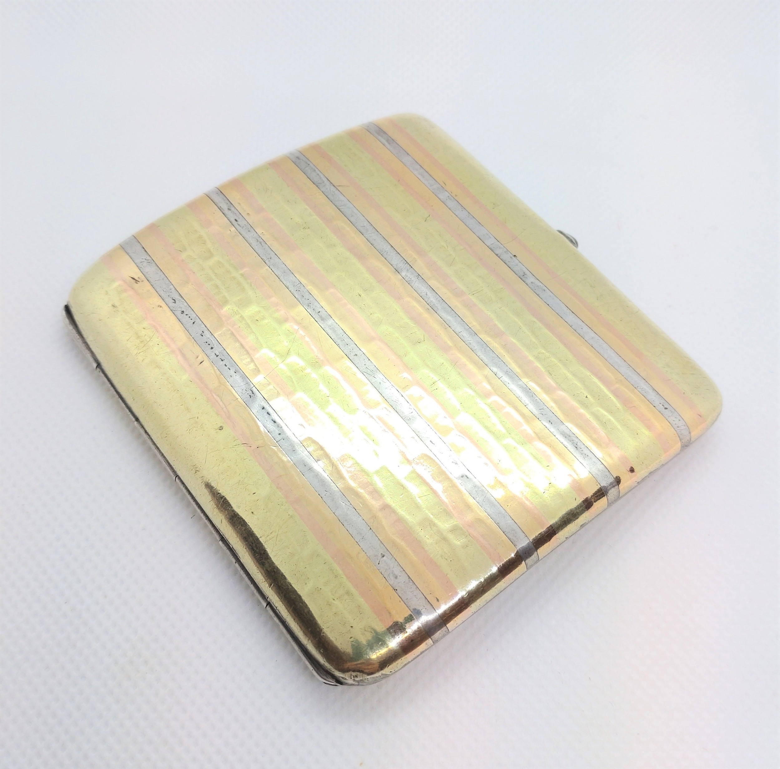 A sterling silver cigarette case with gold pique decoration, apparently unmarked. 8.5cm wide.