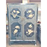 A Chinese Lacquered Two door cabinet. Vintage. With applied floral decoration.