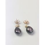 A pair of yellow gold naturally-formed black pearl drop studs with tones of mauve and green.