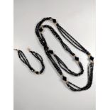 An elegant triple-strand black cut bead necklace with matching bracelet, both with 9ct gold clasps