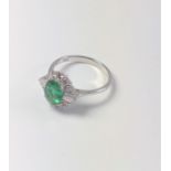 An 18ct white gold ring set with oval emerald, Round Brilliant Cut and tapered baguette diamonds.