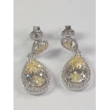 A pair of silver pear shape drop earrings with central yellow pear shaped CZ and white round CZ