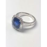 An 18ct white gold ring set with rectangular cushion sapphire surrounded by Round Brilliant Cut