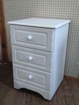 A white bedside chest of drawers.