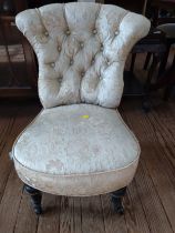 A cream upholstered button back bedroom chair, on four wooden legs.