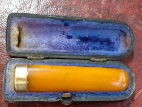 A cased amber cheroot holder with 9ct gold band.