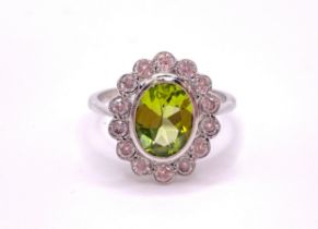 A platinum, diamond, and peridot cluster ring, set with a mixed oval-cut peridot of approximately