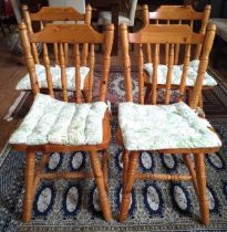 A set of four pinewood spindle-backed kitchen chairs, with removable cushions.