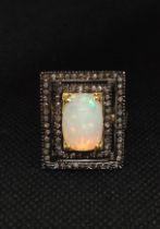 A large rectangular silver gilt dress ring set with an oval cabochon white opal and rose-cut