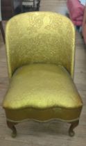 A gold upholstered chair, with rounded back, supported on four cabriole legs.