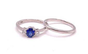 A platinum, diamond, and sapphire ring, set with a mixed oval-cut sapphire, flanked with two round