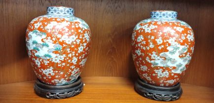 A pair of Japanese porcelain ovoid jars with inner lids and covers, 24cm with pair of hardwood